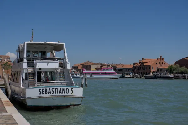 Bateaux dans l'eau azur de la lagune devant les maisons de Murano, Venise.