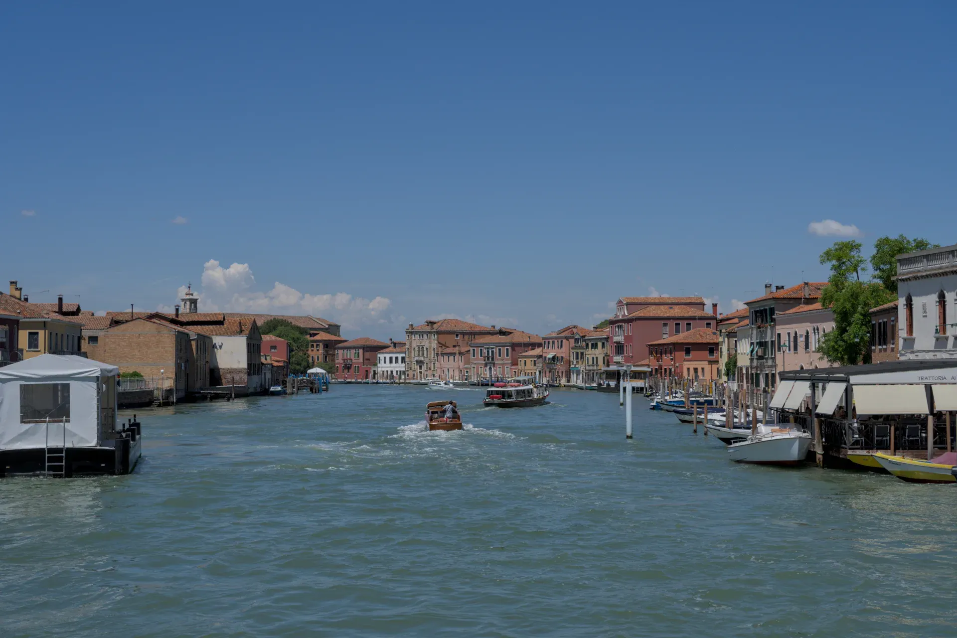 Vista de un canal en Murano, Italia, con edificios coloridos y barcos en el agua.