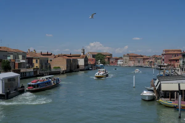 Blick auf einen Kanal auf der Insel Murano in Venedig mit Booten und traditionellen Gebäuden.