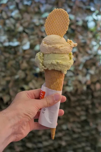 Hand hält doppeltes Pistazieneis in einer Waffel mit Waffelspitze, aufgenommen auf Murano.