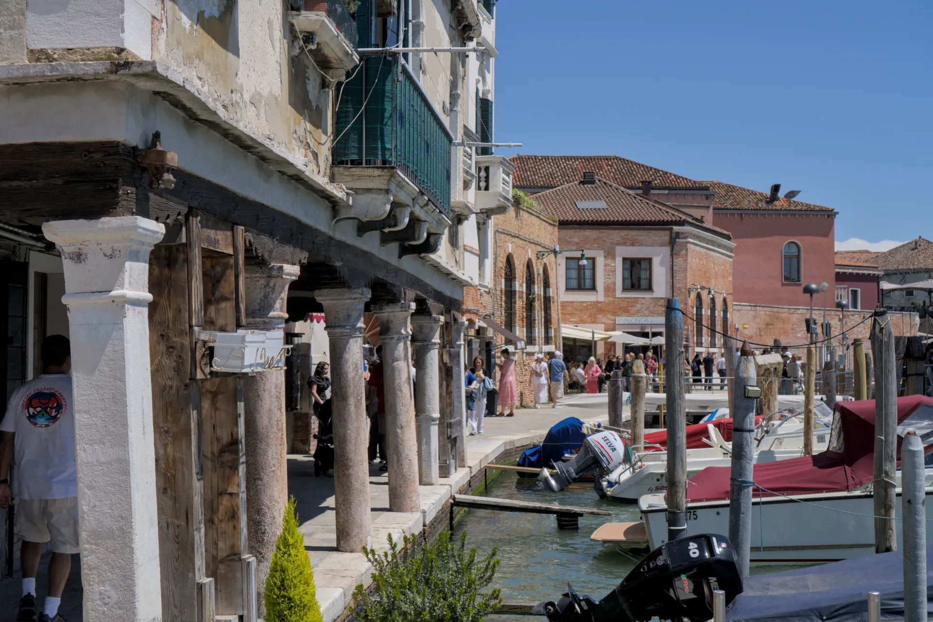 View of the canal on Murano Island in Venice with boats and traditional buildings.