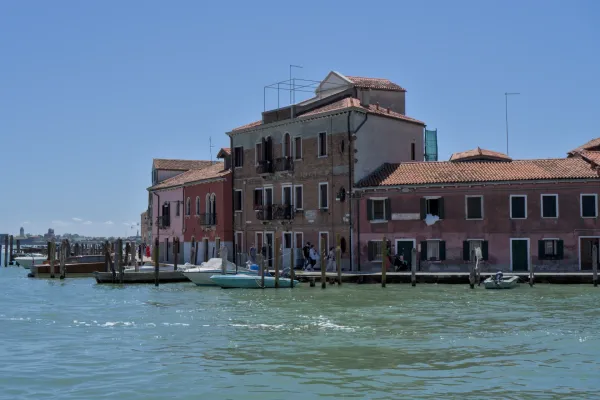 Šarene kuće i čamci na obali ostrva Murano, Venecija, pri dnevnom svetlu.