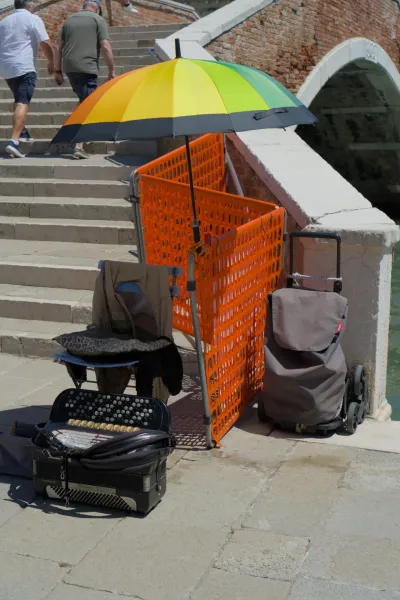 Harmonika i šareni kišobran na ostrvu Murano u Veneciji, Italija, sa kanalom u pozadini.