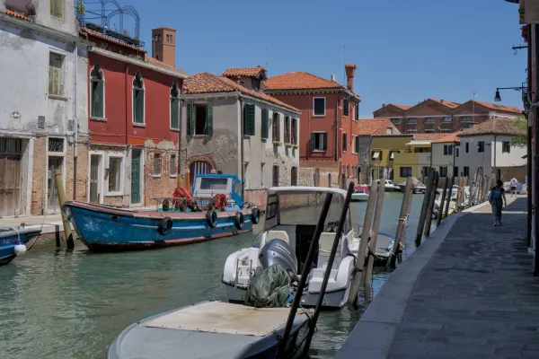 Ein malerischer Kanal auf der Insel Murano in Venedig mit traditionellen Booten und bunten Häusern.