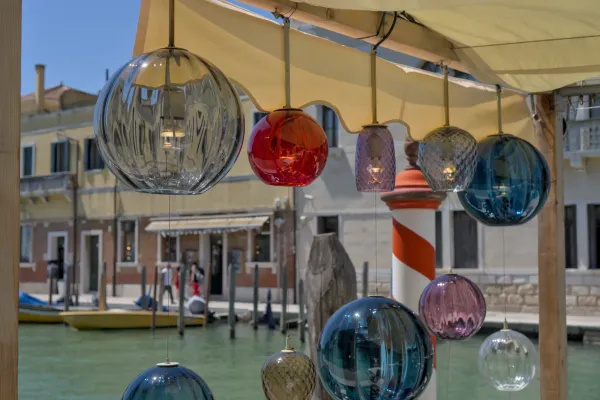 Viseći stakleni lusteri od Murana u raznim bojama iznad vodenog kanala u Veneciji, Italija.