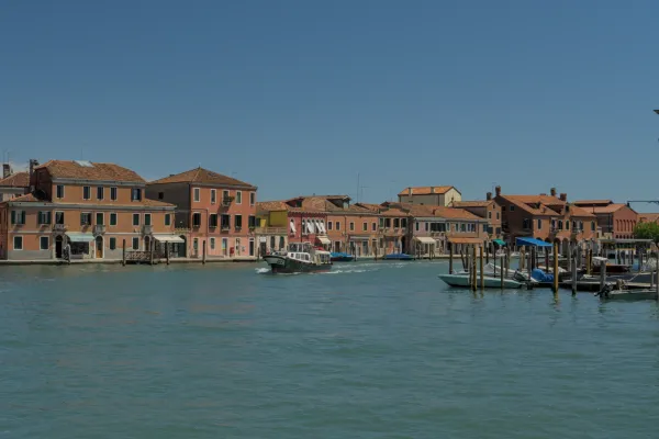 Pogled na kanal Murano sa šarenim kućama i prolaznim čamcem.