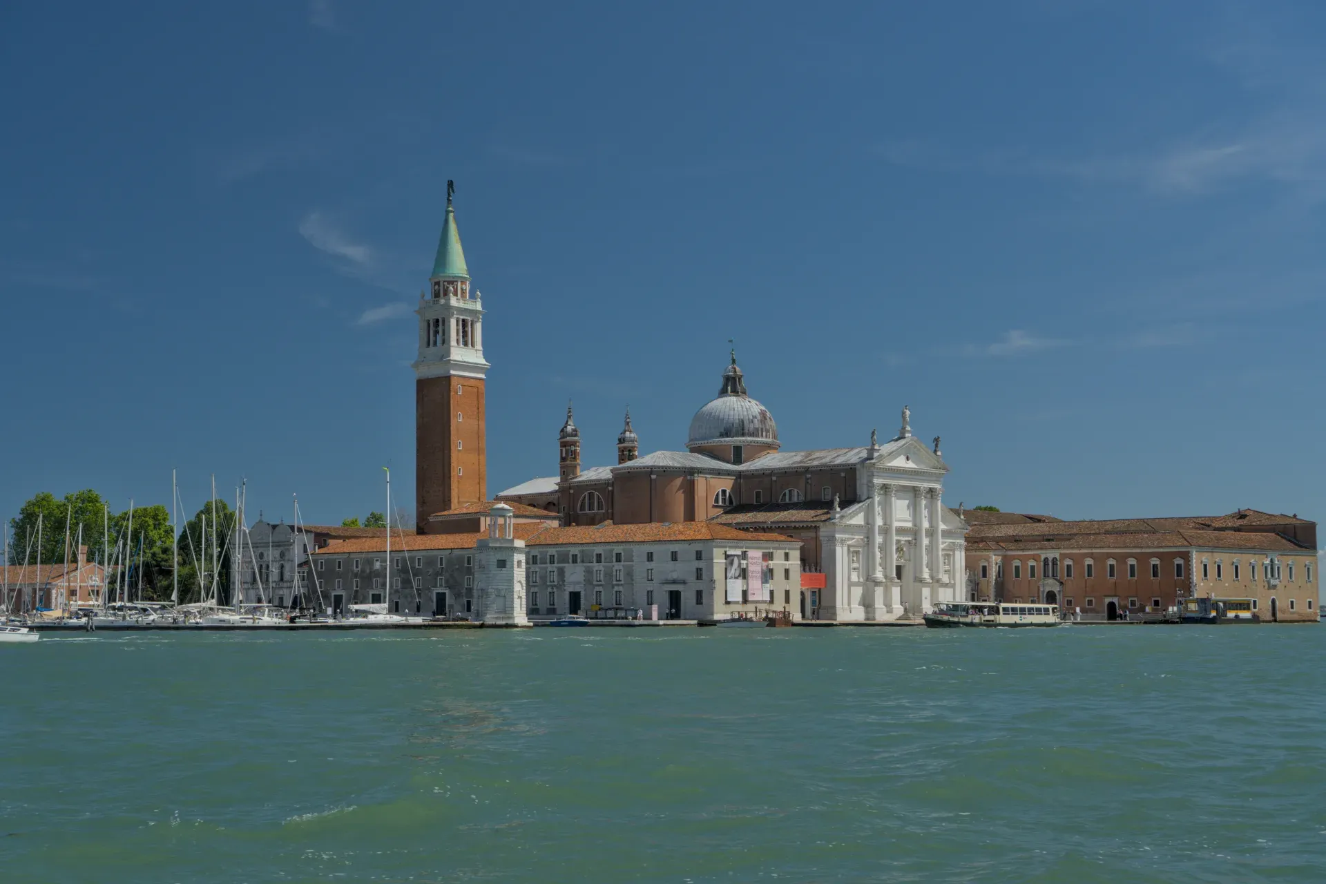 The Basilica of San Giorgio Maggiore with its campanile in Venice, Italy, against a clear blue sky and calm water.