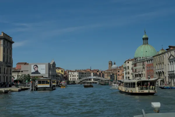 Veliki kanal u Veneciji sa šarenim zgradama, čamcima i Bazilikom Santa Maria della Salute u pozadini.