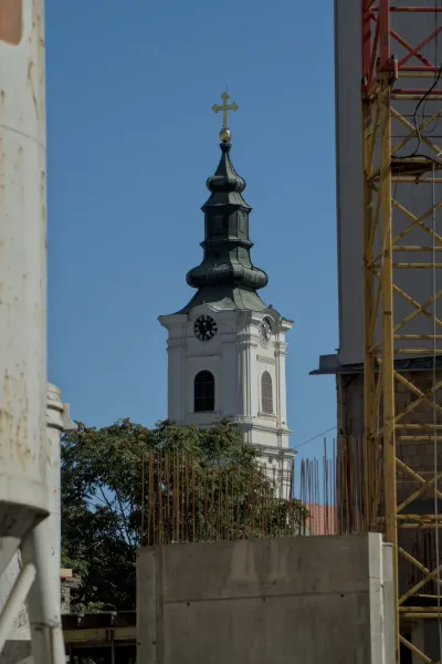 Il campanile della Cattedrale della Dormizione a Novi Sad si erge contro un cielo azzurro limpido, con il suo tetto verde e la croce dorata.