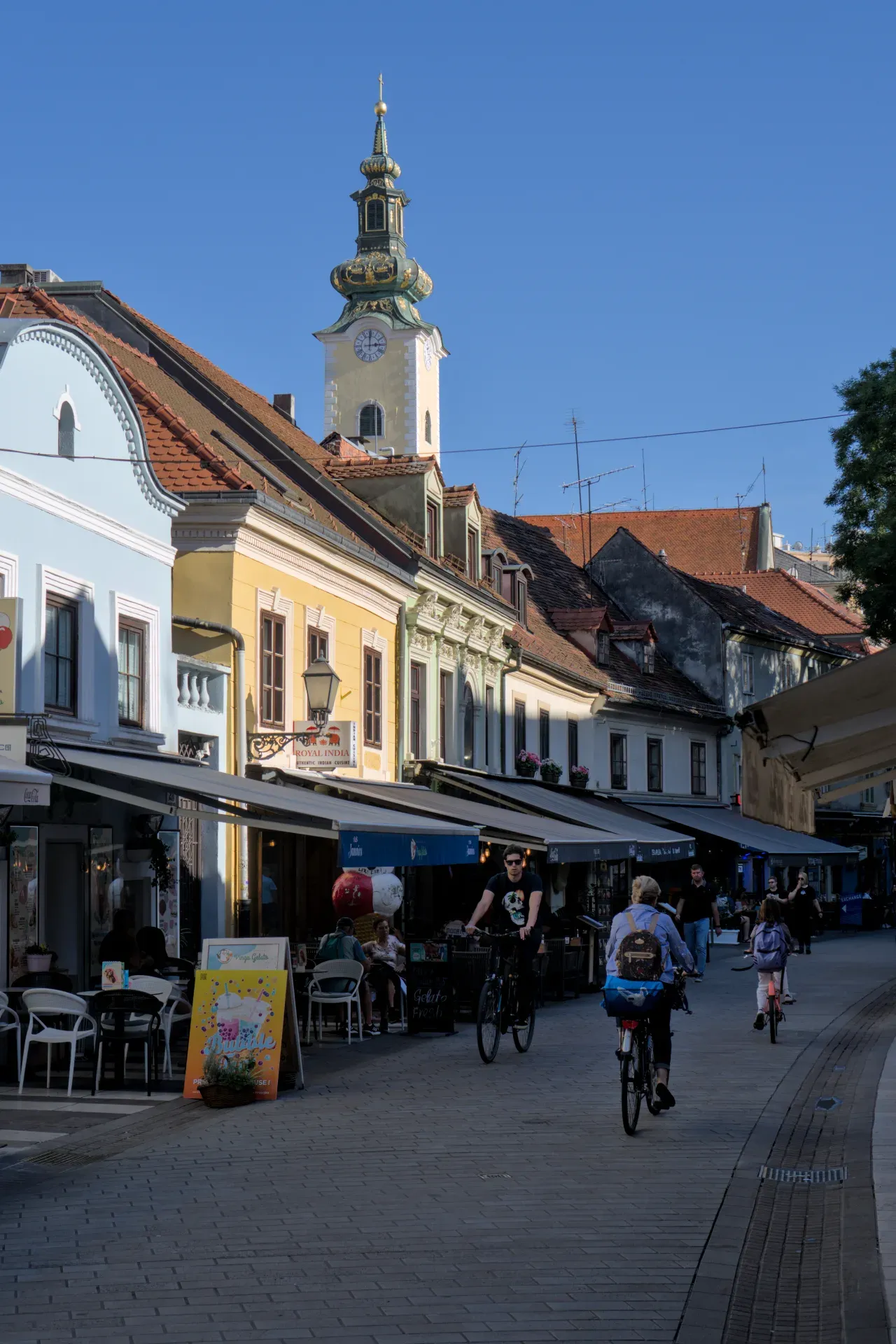 A charming image of an alley in Zagreb with a prominent church tower gleaming in the sunlight.