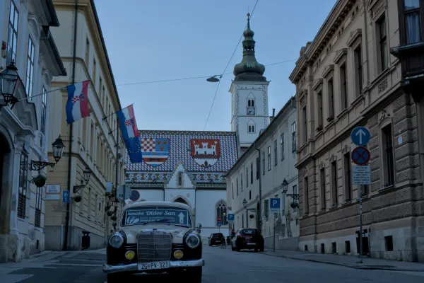 Voiture classique et église Saint-Marc à Zagreb avec des drapeaux croates au crépuscule.