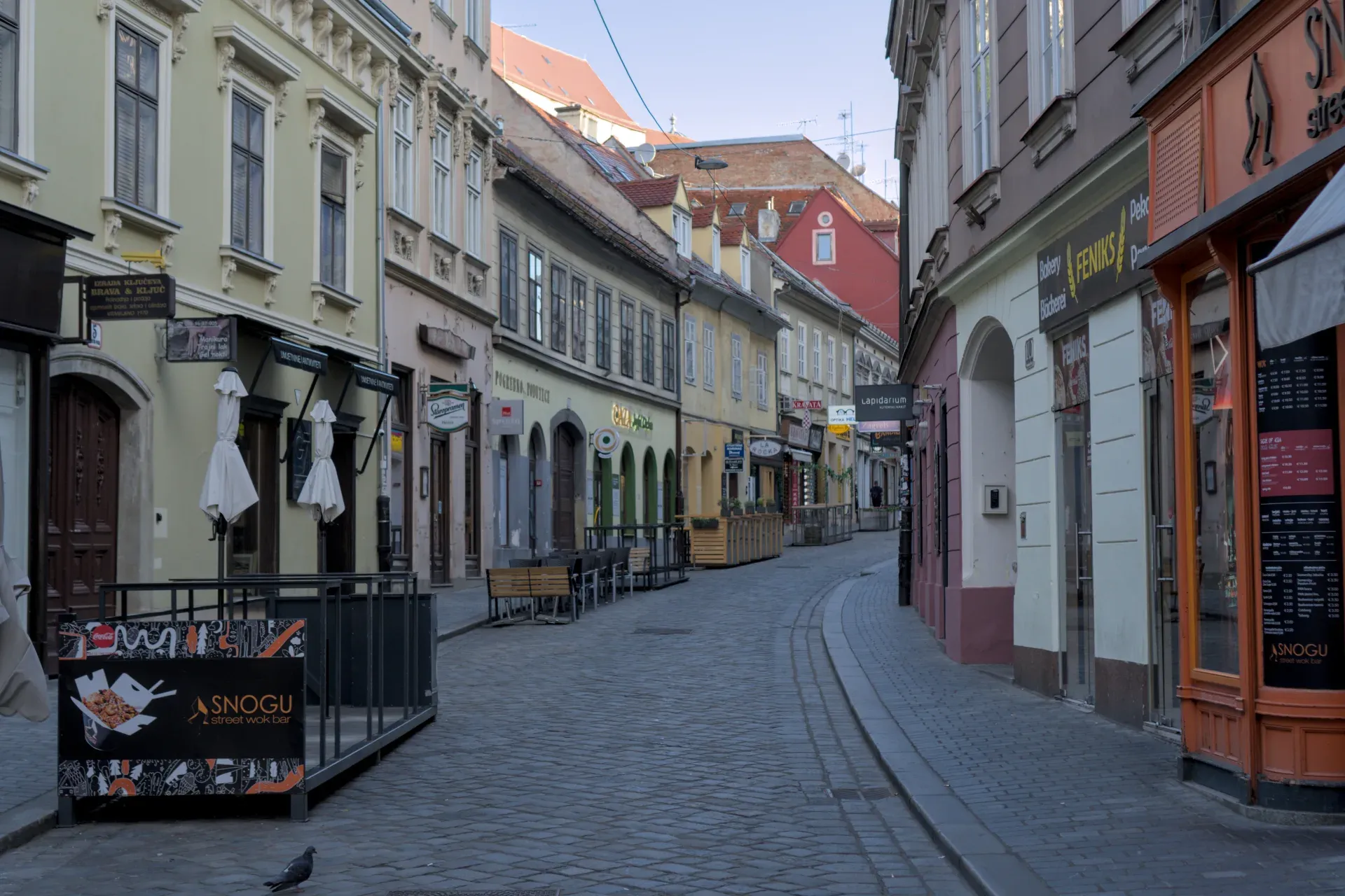 A narrow, cobblestone alley in Zagreb with historic buildings and shops, captured in landscape format.