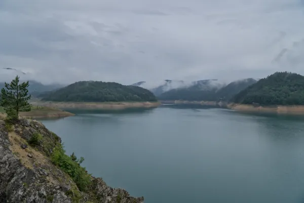 Nubes densas y niebla sobre el lago Zaovine en Serbia, con colinas verdes al fondo.