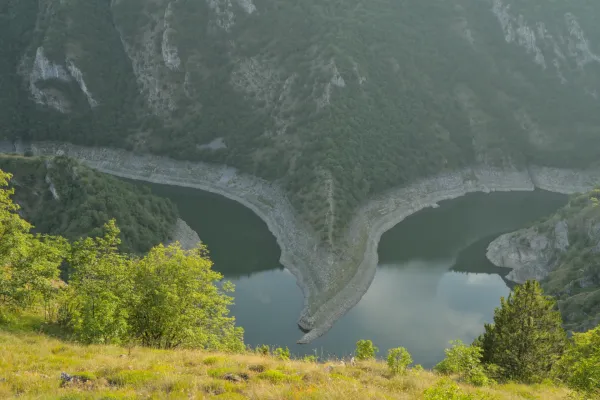 Mäander des Flusses Uvac in Serbien bei Sonnenuntergang, umgeben von bewaldeten Hügeln.