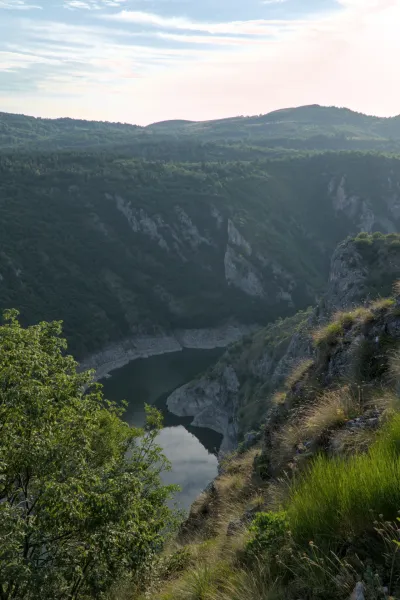 Die Uvac-Schluchten bei Sonnenuntergang mit einem ruhigen Fluss und Bergen.