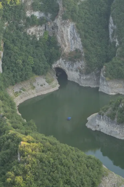 Ein blaues Boot fährt auf dem Fluss in Richtung der Ušac-Höhle in der Uvac-Schlucht, Serbien.