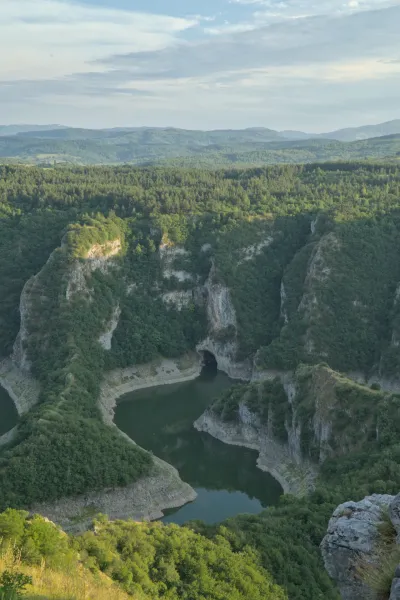 Panoramski pogled na Uvačku klisuru u Srbiji sa dubokom zelenom dolinom, rekom i pošumljenim padinama.