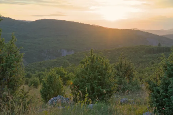 Zalazak sunca na uzvišenju "Molitva" u Uvcu, Srbija, sa blagim brdima i toplim svetlom.