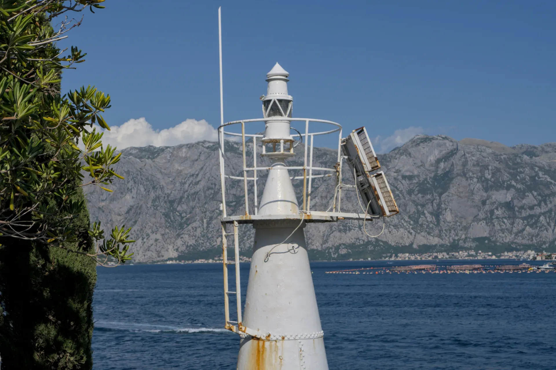 Phare à l'entrée de la baie de Kotor, Monténégro, avec la mer turquoise et les montagnes en arrière-plan.