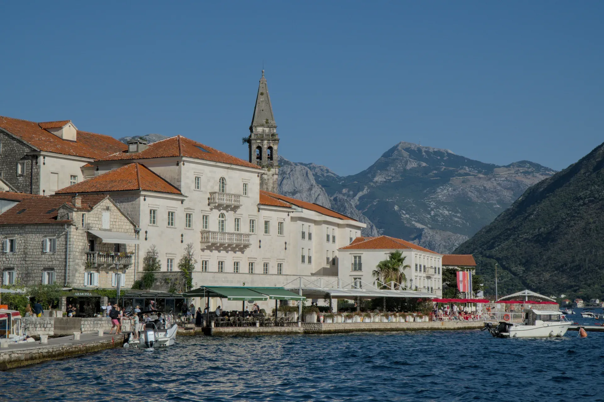 Coucher de soleil à Perast, Monténégro, avec une lumière dorée sur les bâtiments historiques et les montagnes en arrière-plan.