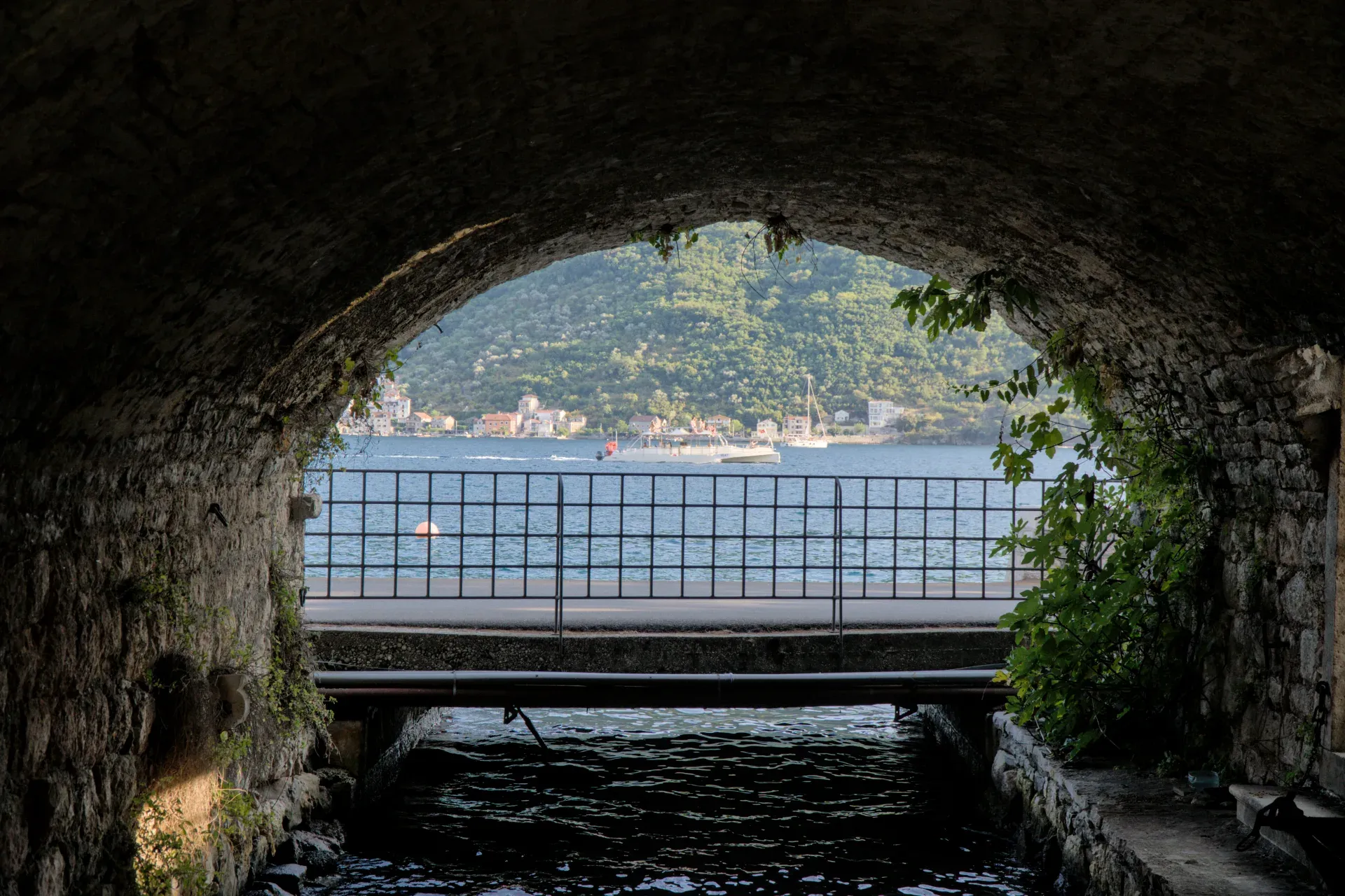 Sea view with boat and architecture through a stone arched passage in Perast, Kotor.