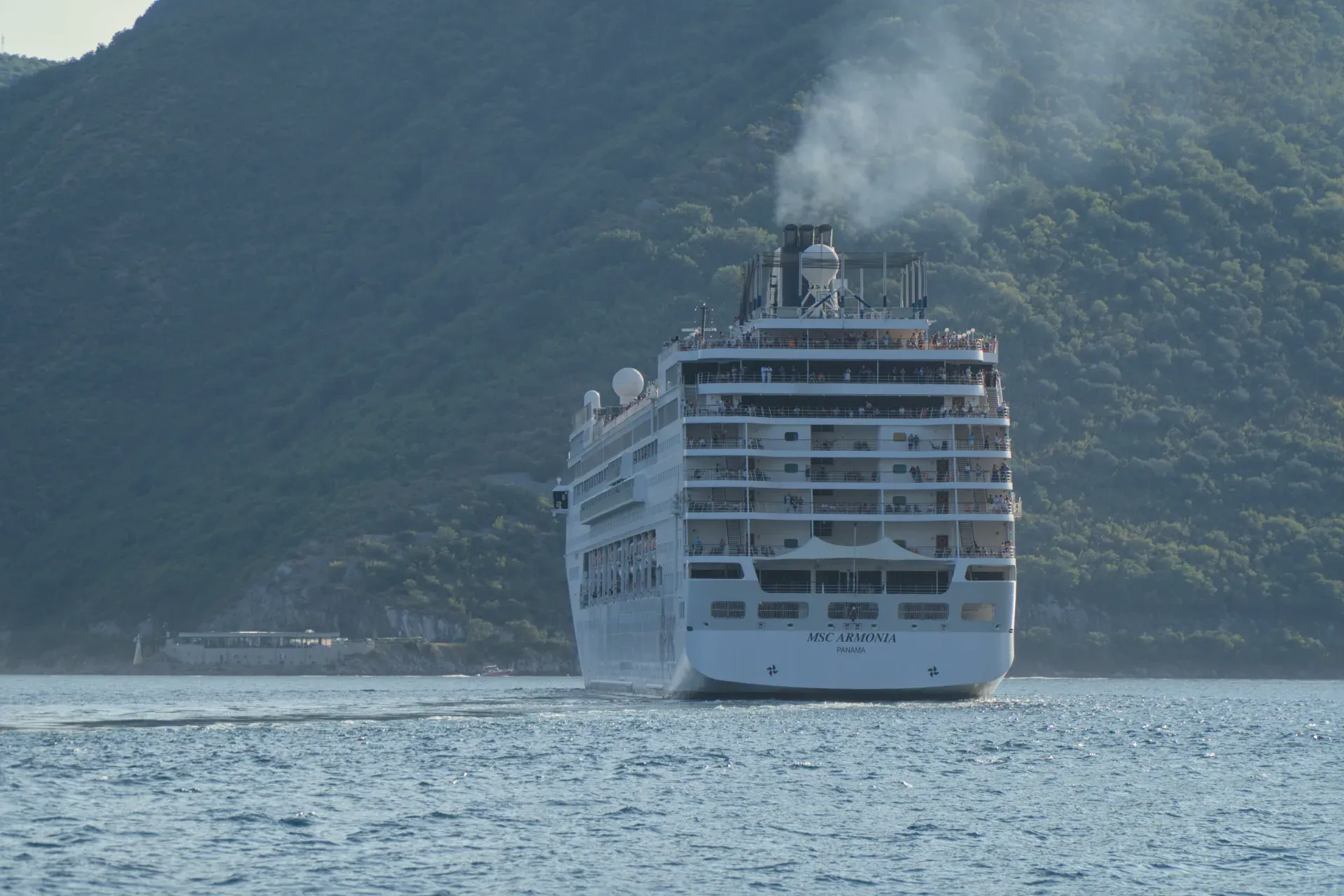 A large cruise ship, the MSC Armonia, steams away from the Bay of Kotor, Montenegro.