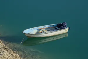 Una barca blanca con acentos azules flota amarrada en las tranquilas aguas turquesas del lago Zaozisko al amanecer.