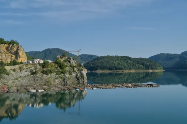 Idilio matutino en el Lago Zaovine del Parque Nacional de Tara, Serbia, con aguas tranquilas y colinas boscosas.