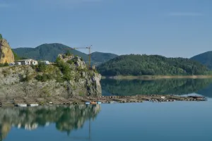 Lago Zaovine Serbia al amanecer con aguas tranquilas reflejando montañas verdes, ideal para decoración de paredes.