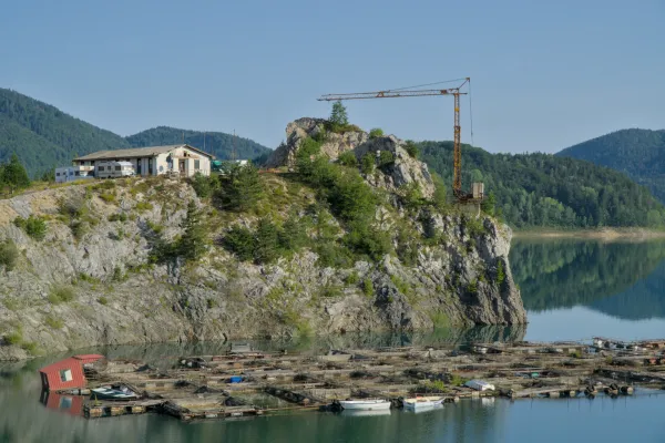 Luz colorida de la mañana sobre el Lago Zaovine en Serbia, con montañas y piscifactorías.