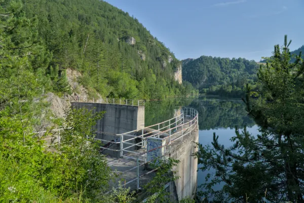 Barrage Lypovica à Zaovine, Parc National Tara, Serbie, avec des montagnes vertes à l'arrière-plan et des reflets dans l'eau.