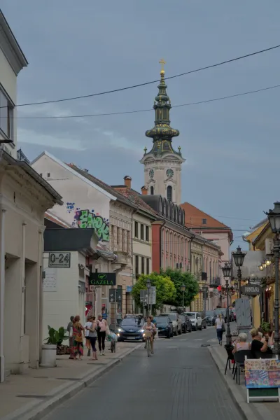 Ulica Nikole Pašića u Novom Sadu, Srbija, sa pogledom na crkvu Svetog Đorđa i živopisnom urbanom arhitekturom.