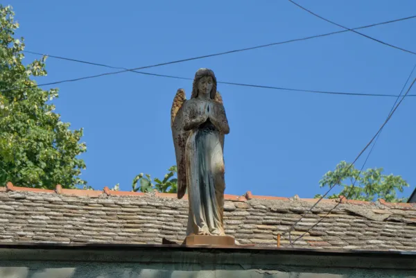 Una scultura di un angelo sul tetto di una casa a Novi Sad, Serbia, contro un cielo blu.