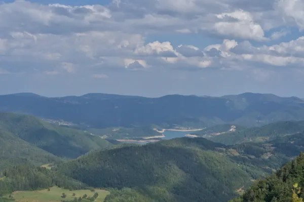 Панорамный вид на озеро Заовине с горы Яньач, Сербия, с зелеными горами и облаками.