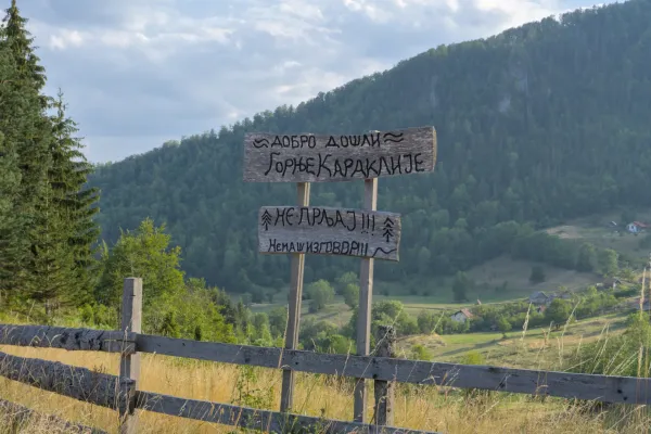 Un cartello serbo divertente con scritte dipinte a mano a Gornje Karajlić, Parco Nazionale di Tara, Serbia, sullo sfondo di montagne.