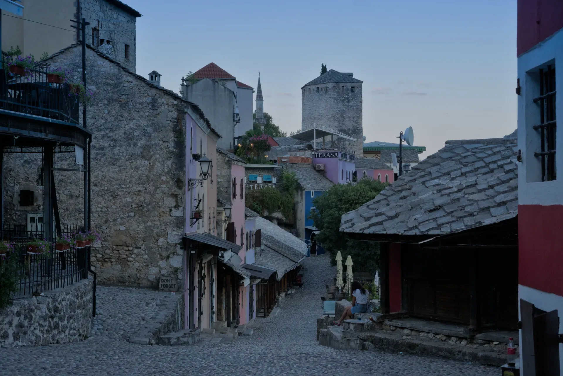 Cobblestone street in Mostar's Old Town during predarassvetny chas, with historic buildings in soft twilight.
