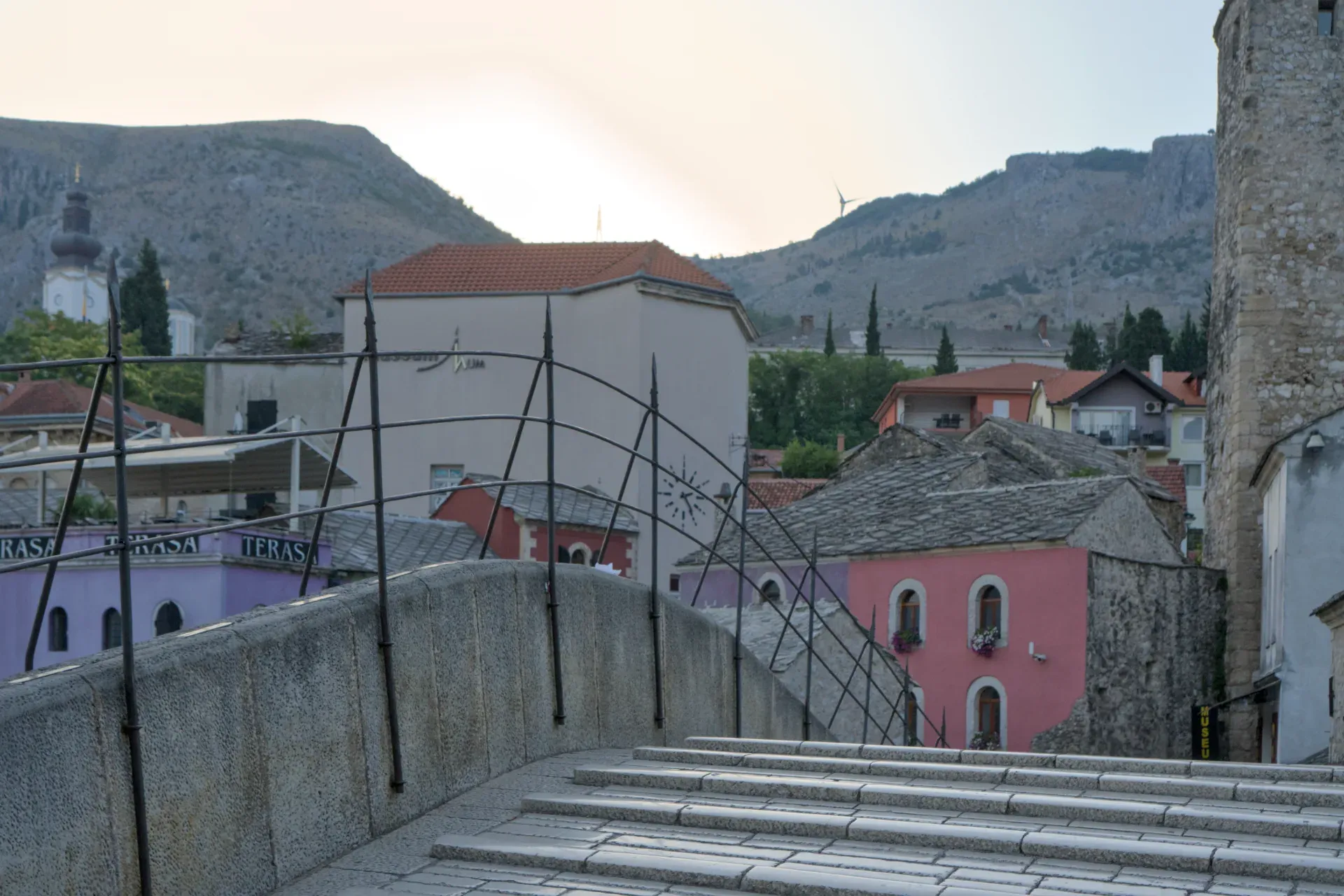 View from the Old Bridge of Mostar at sunrise, bathed in golden light.