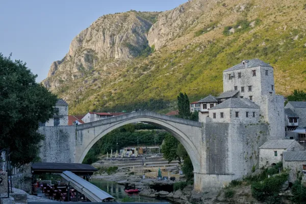 Il Ponte Vecchio (Stari Most) a Mostar all'alba, con sfondo montuoso e fiume.
