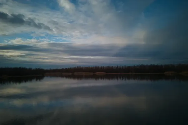 Pejzažna fotografija Begečke jame u Srbiji, prikazuje dramatično nebo i odraz u vodi.