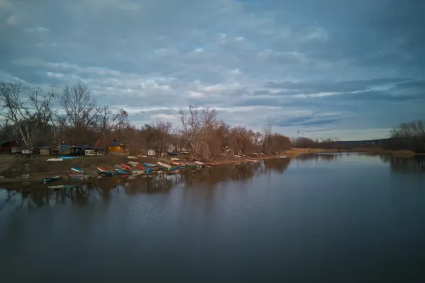 Čamci na mirnoj obali Begečke Jame, Novi Sad, Srbija, pod dramatičnim, oblačnim nebom.
