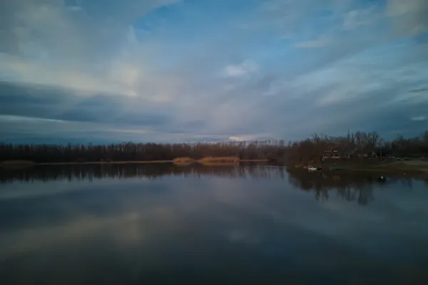 Calm lake reflecting the sky and treeline at Begečka Jama, Novi Sad
