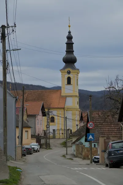The Church of the Transfiguration in Beočin, Serbia, with its distinctive yellow and white bell tower, under an overcast sky.