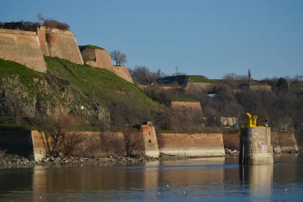 Pogled na Dunav i starinske ciglane zidove Petrovaradinske tvrđave pod vedrim nebom.