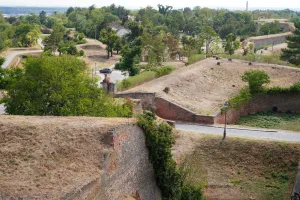 View of the historic Petrovaradin Fortress in Novi Sad, Serbia, with its ancient brick ramparts and green landscape.