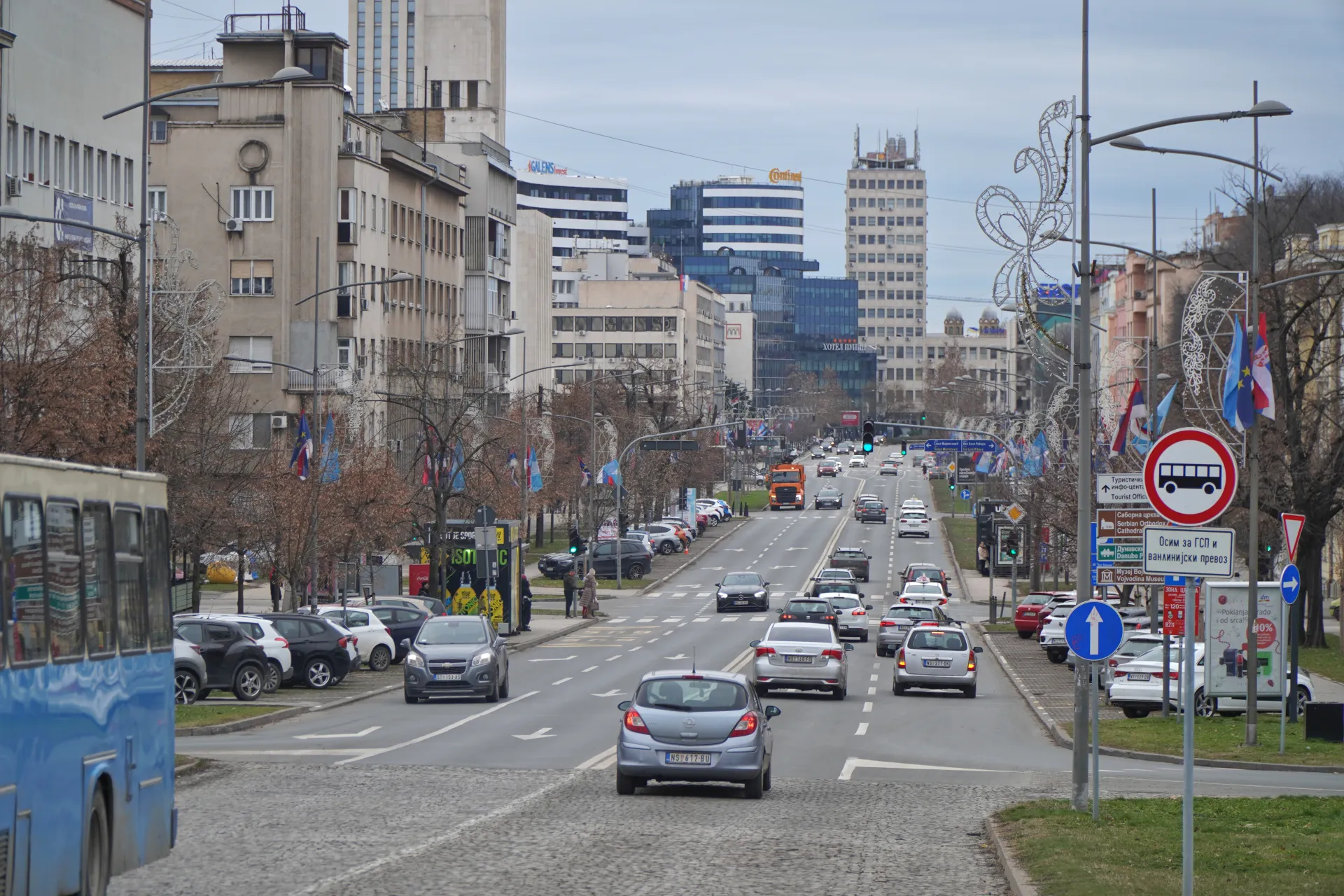 Ulica u Novom Sadu, Srbija, sa saobraćajem, pešačkim prelazima i zgradama sa obe strane.