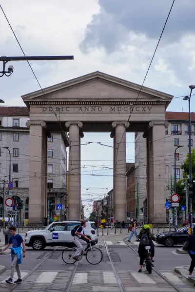 Ein Blick auf eine Kopfsteinpflasterstraße in Mailand, Italien, flankiert von bunten Gebäuden mit schmiedeeisernen Balkonen und geschlossenen Fensterläden.