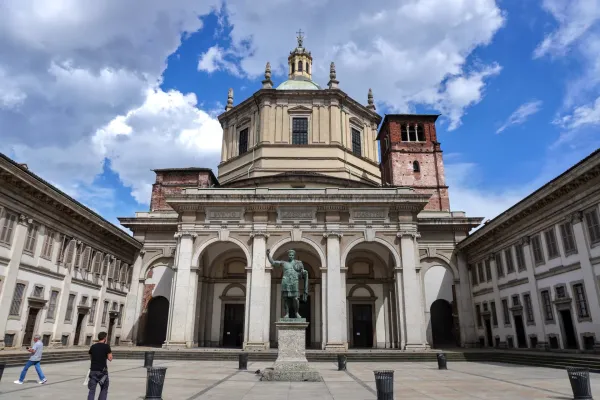 Fassade der Basilica di San Lorenzo Maggiore in Mailand, Italien, mit einer Statue eines römischen Kaisers und einer großen Kuppel unter einem bewölkten Himmel.