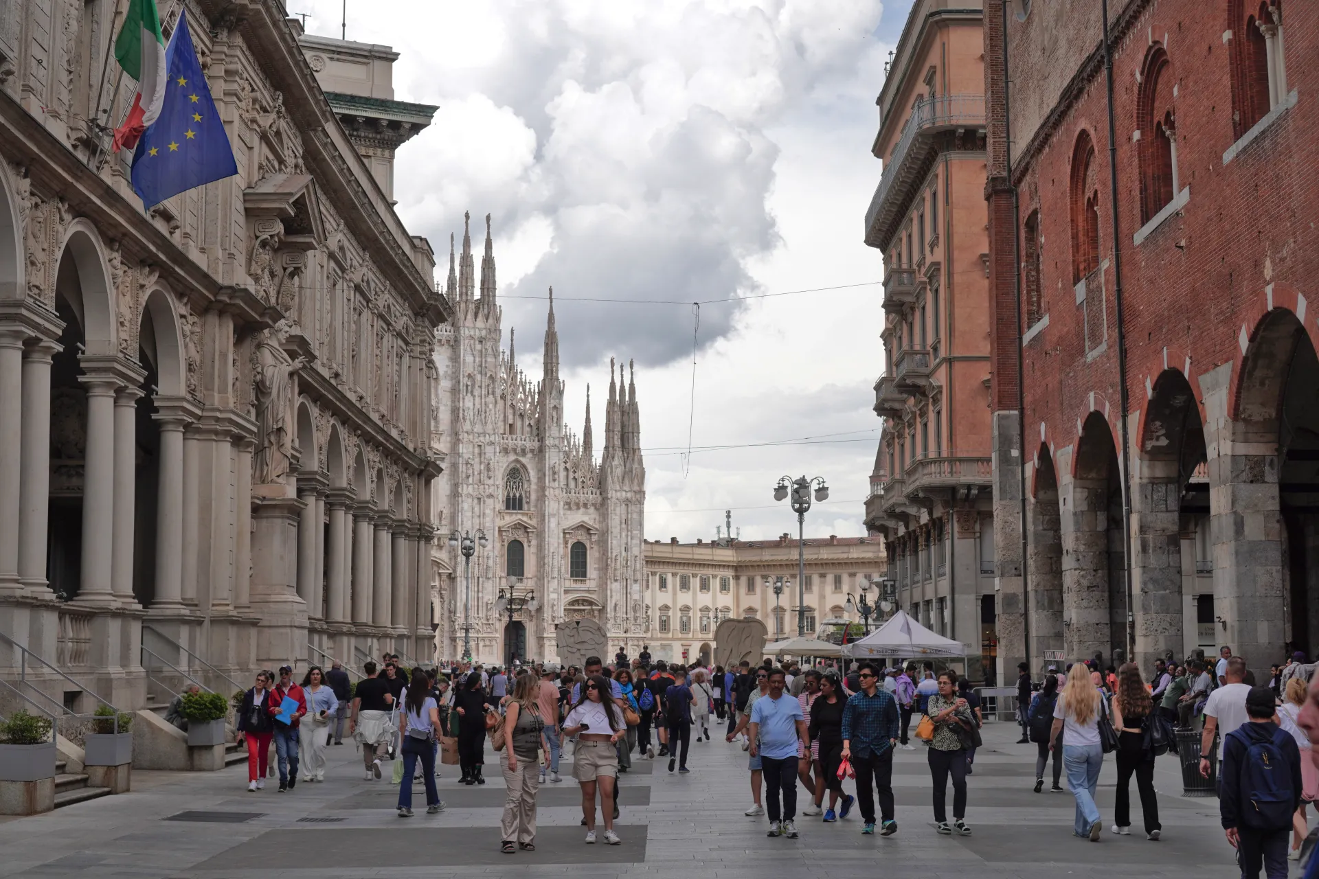 Široki kadar Trga Duomo u Milanu, Italija, sa ikoničnom Milanskom katedralom u pozadini i mnogo ljudi koji šetaju trgom.