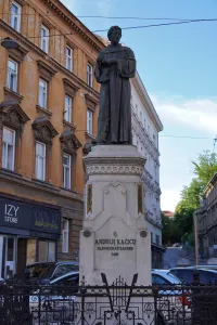 Statue of Andrija Kačić Miošić on a pedestal in Zagreb, Croatia, with an old building in the background.