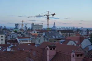 View of Zagreb's rooftops and construction cranes against a twilight sky.